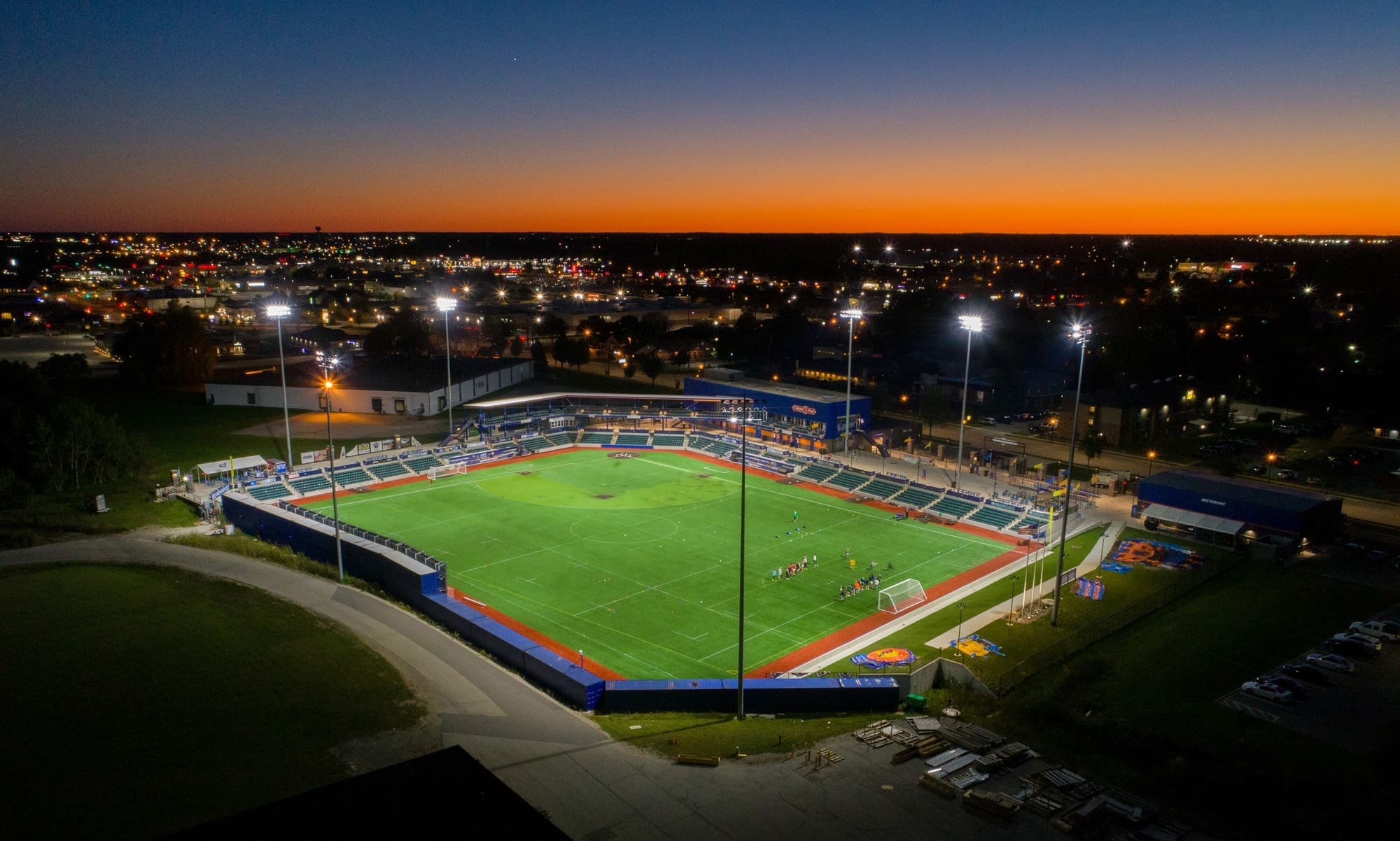 Commercial outdoor soccer stadium property illuminated at dusk, cityscape views and sunset sky, ideal for real estate showcase. Commercial outdoor soccer stadium property illuminated at dusk, cityscape views and sunset sky, ideal for real estate showcase.