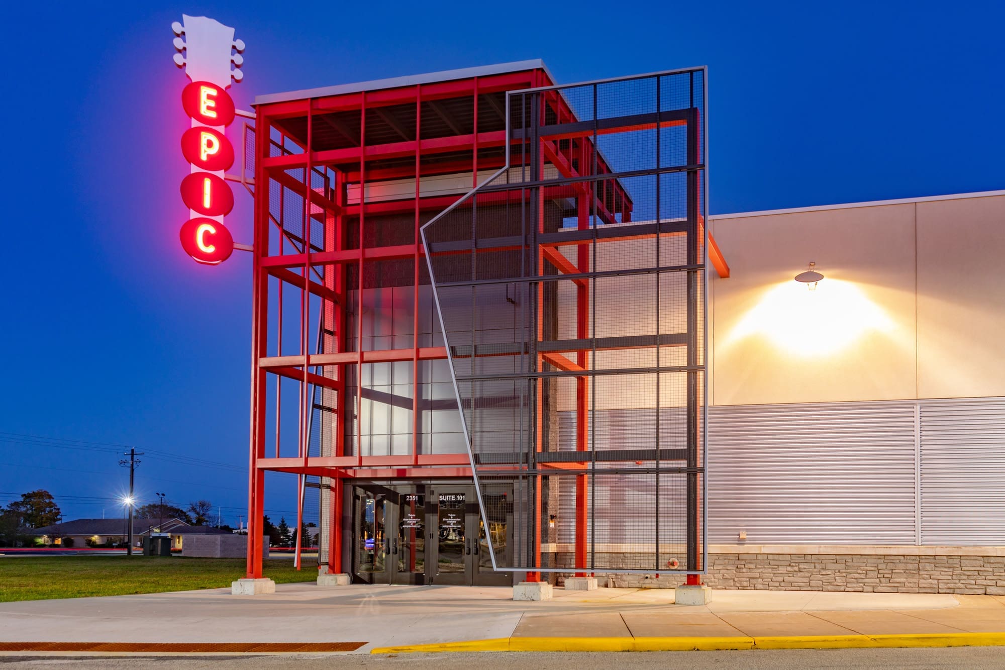 Commercial property exterior at dusk, modern architecture with red accents and EPIC neon sign above main entrance, ideal real estate listing. Commercial property exterior at dusk, modern architecture with red accents and EPIC neon sign above main entrance, ideal real estate listing.