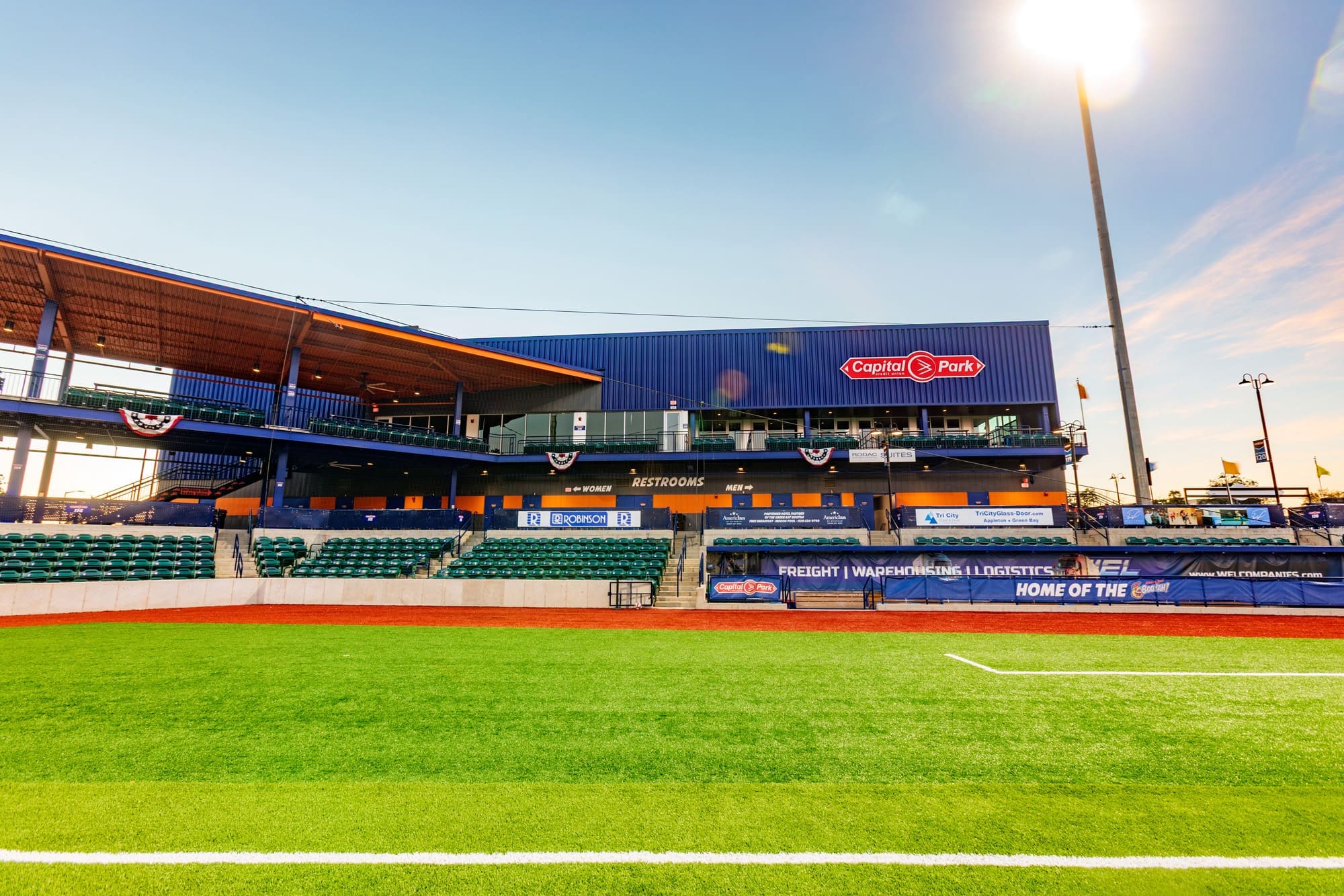 Commercial property photo of Capitol Park baseball stadium featuring green seats, blue grandstand, and sunset sky—ideal investment.