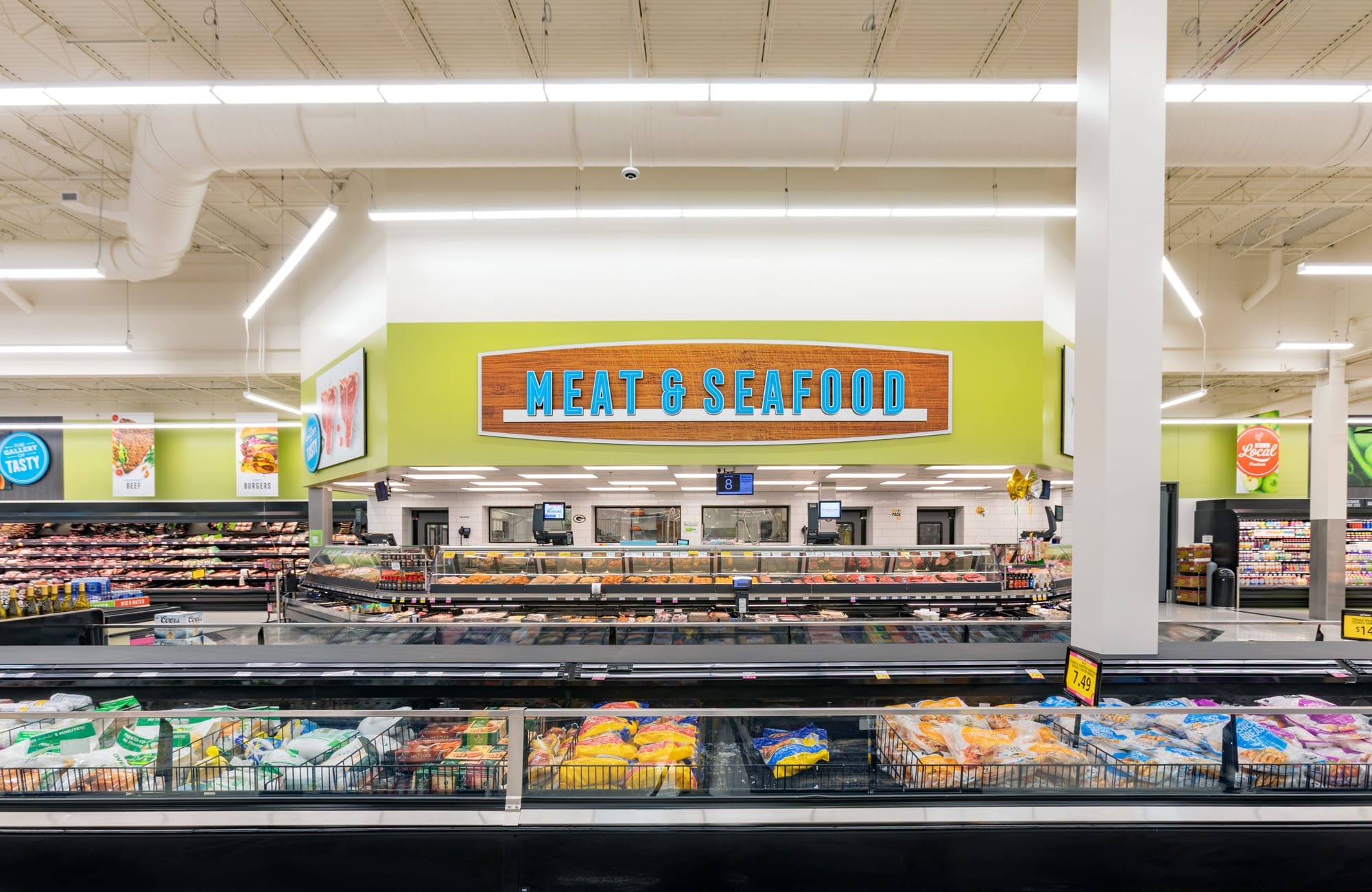 Commercial real estate photo of grocery store meat and seafood section, showcasing modern freezers and spacious service counter.